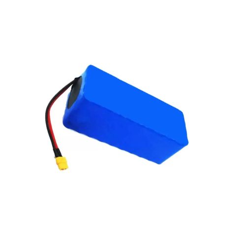 Juodas elektrinis krosinis motociklas geltonais akcentais žalios dirbtinės žolės sienos fone.